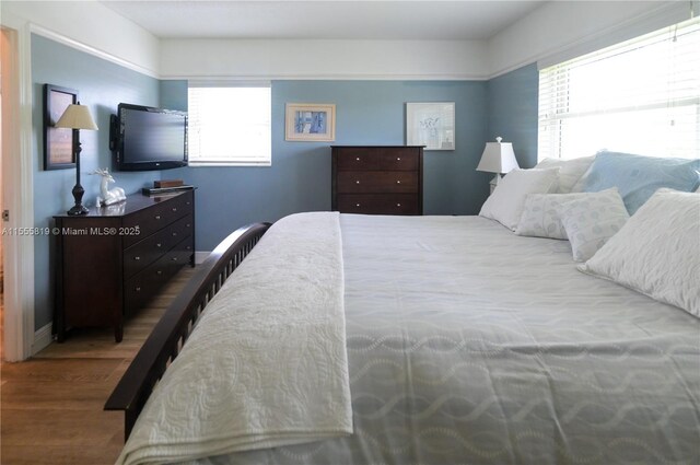 bedroom with hardwood / wood-style flooring and multiple windows