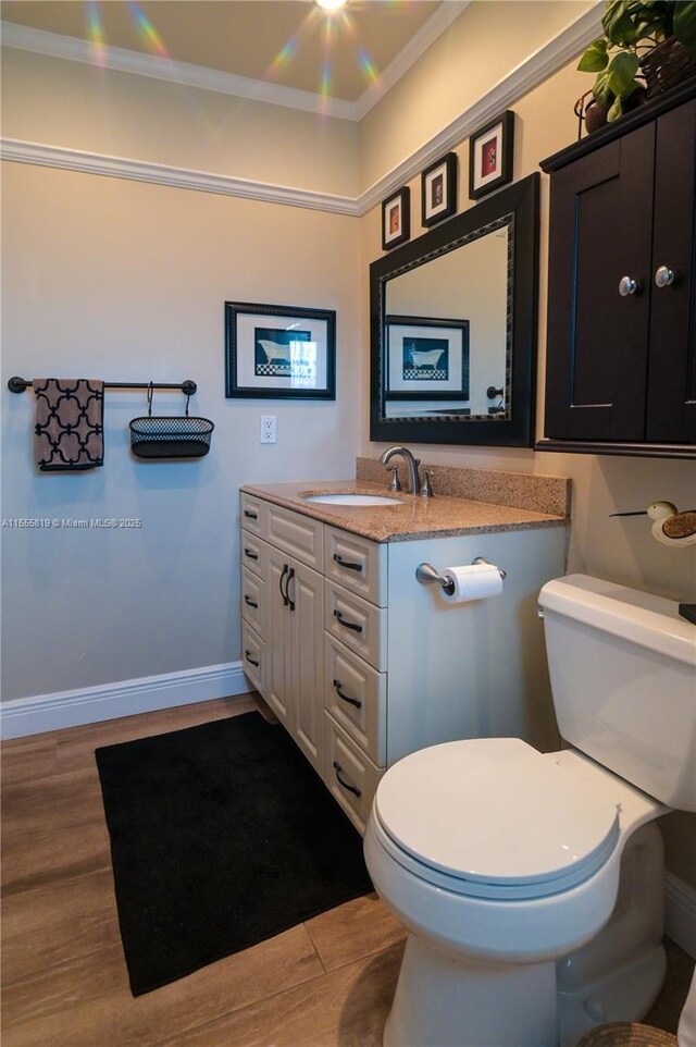 bathroom with vanity, toilet, wood-type flooring, and ornamental molding