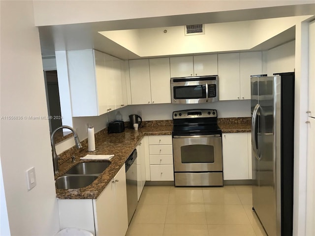 kitchen with dark stone counters, light tile floors, appliances with stainless steel finishes, and sink