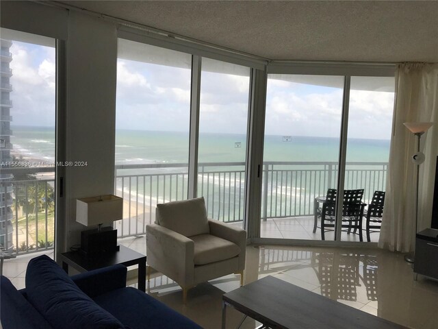 living room with a textured ceiling, floor to ceiling windows, a healthy amount of sunlight, and a water view