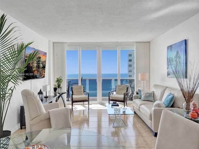 living room featuring a textured ceiling, floor to ceiling windows, and a water view