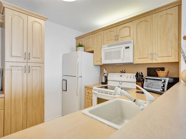 kitchen featuring white appliances, light brown cabinets, and sink