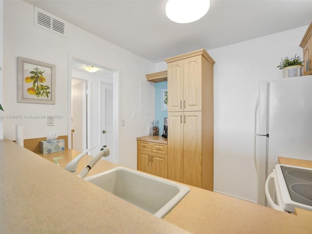 kitchen featuring white range, light brown cabinetry, and sink