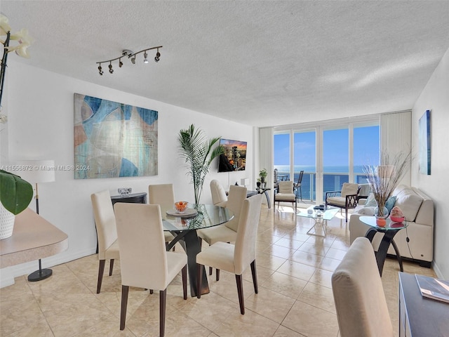 dining space with a water view, a textured ceiling, light tile patterned floors, and expansive windows