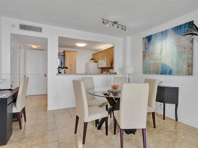 tiled dining space with a textured ceiling