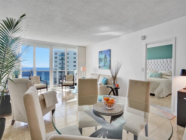 tiled dining area with a textured ceiling, a wall of windows, and a water view