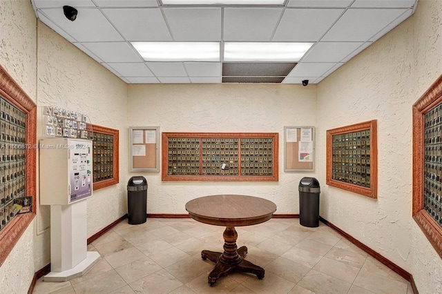 hallway with a paneled ceiling and light tile patterned floors