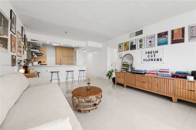 living room featuring sink, a textured ceiling, and light tile flooring