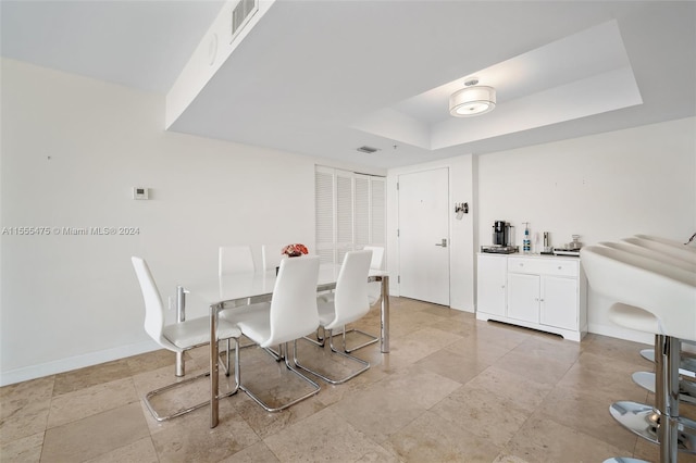 tiled dining room with a tray ceiling