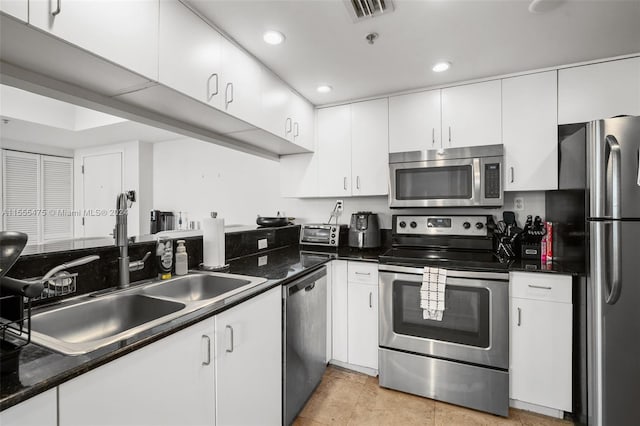 kitchen featuring stainless steel appliances, light tile flooring, white cabinetry, and sink