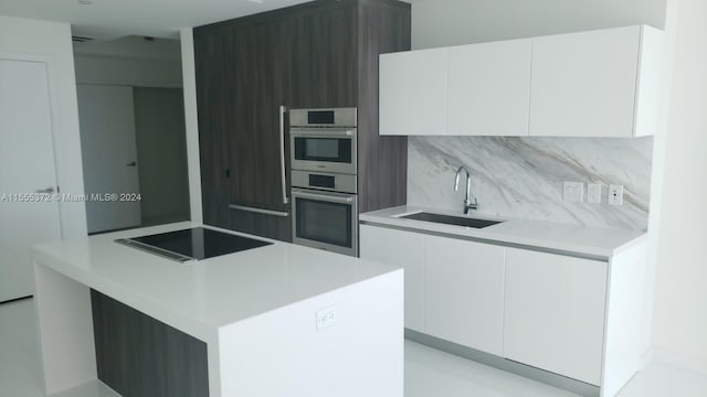 kitchen with white cabinetry, stainless steel double oven, black electric cooktop, sink, and tasteful backsplash