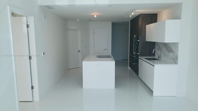 kitchen with white cabinets, sink, backsplash, and light tile floors