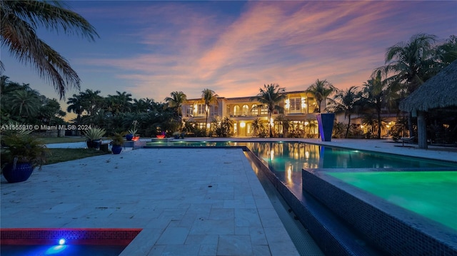 pool at dusk featuring a patio