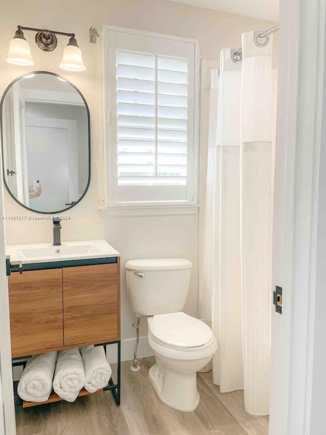 bathroom featuring toilet, oversized vanity, and wood-type flooring