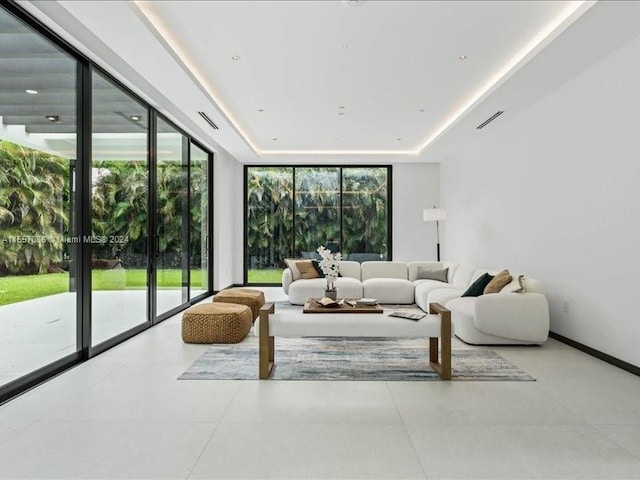 tiled living room featuring a wealth of natural light and a tray ceiling