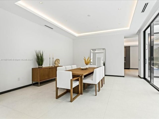 dining space featuring light tile patterned flooring and a raised ceiling