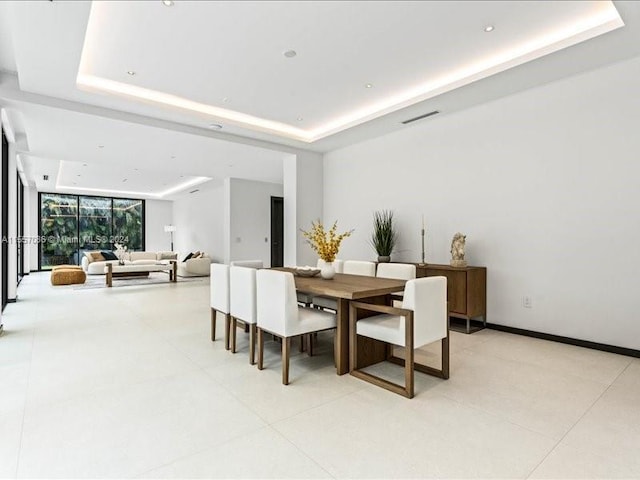 dining room featuring a tray ceiling and light tile patterned floors