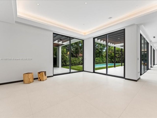 spare room featuring a raised ceiling and tile patterned flooring