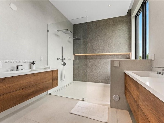 bathroom featuring tile patterned floors, a tile shower, and vanity