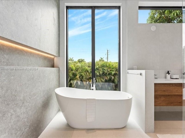 bathroom with tile patterned floors, tile walls, vanity, and a tub to relax in