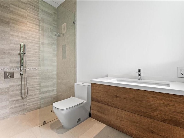 bathroom with tile patterned floors, toilet, a tile shower, and vanity