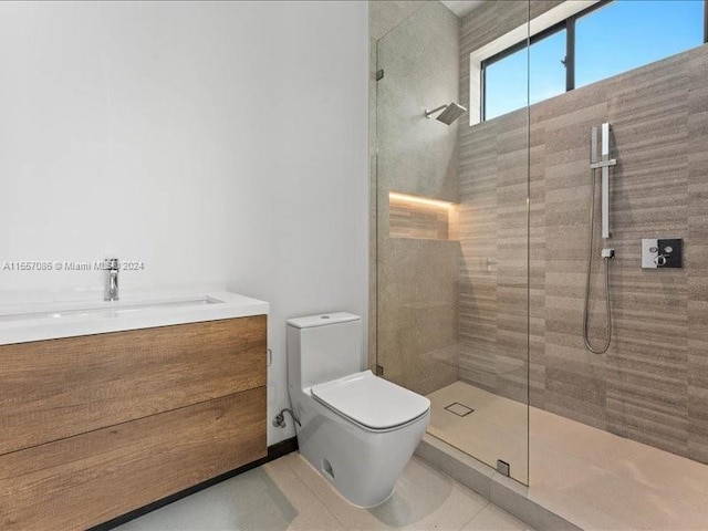 bathroom with toilet, vanity, tiled shower, and tile patterned floors