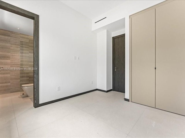 unfurnished bedroom with ensuite bathroom and light tile patterned floors