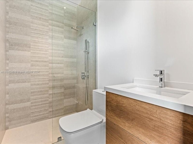 bathroom with a shower with shower door, vanity, and toilet