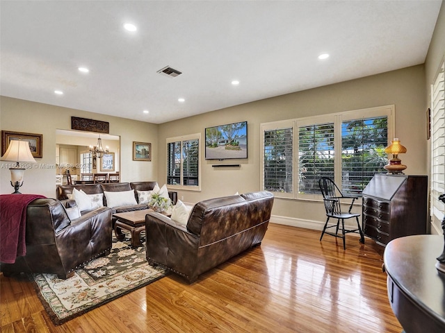 living room featuring a notable chandelier and light wood-type flooring