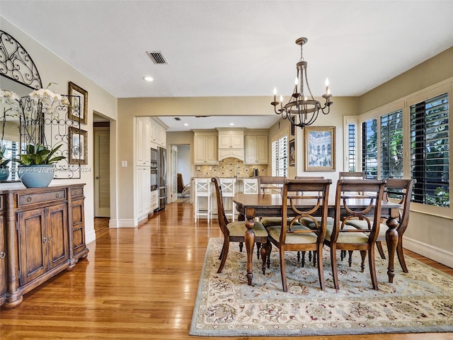 dining room featuring plenty of natural light, a notable chandelier, and light wood-type flooring