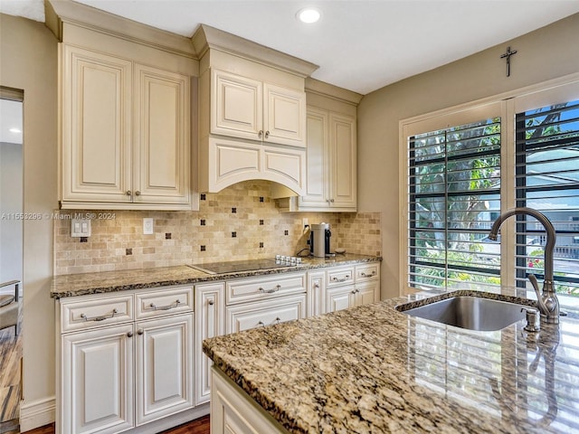 kitchen with light stone countertops, tasteful backsplash, and black electric stovetop