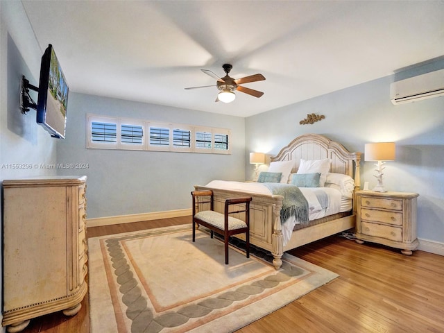 bedroom featuring an AC wall unit, ceiling fan, and light hardwood / wood-style flooring