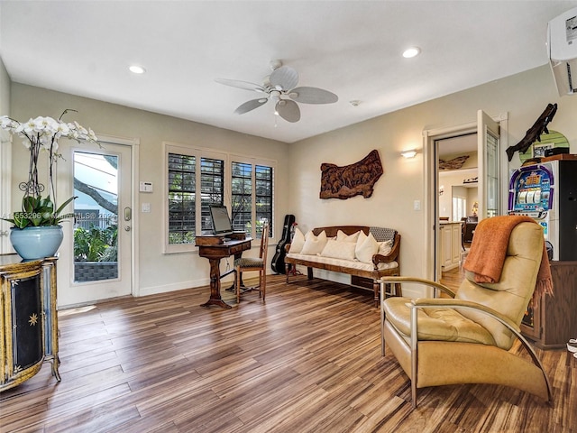 living area featuring ceiling fan, a wealth of natural light, a wall unit AC, and light hardwood / wood-style floors