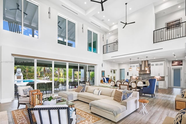 living room with light hardwood / wood-style flooring, coffered ceiling, ceiling fan, and a high ceiling