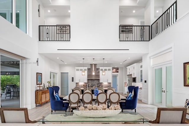 living room featuring light hardwood / wood-style flooring, a high ceiling, and french doors