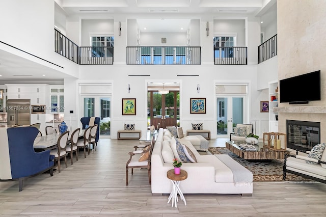 living room with french doors, light hardwood / wood-style floors, and a towering ceiling