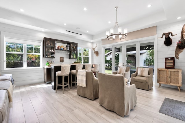 living room featuring a tray ceiling, light hardwood / wood-style flooring, french doors, and an inviting chandelier