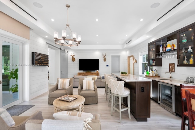 interior space featuring an inviting chandelier, wine cooler, a kitchen island, a breakfast bar area, and pendant lighting