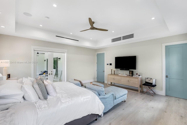 bedroom with a tray ceiling, access to exterior, ceiling fan, light hardwood / wood-style floors, and french doors