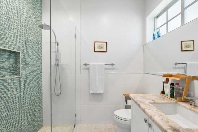 bathroom featuring tile walls, toilet, a shower with door, tile flooring, and vanity