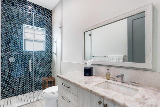 bathroom with vanity, a tile shower, and toilet