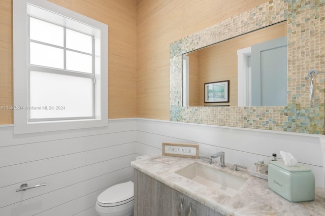 bathroom featuring tile walls, toilet, a healthy amount of sunlight, and vanity with extensive cabinet space