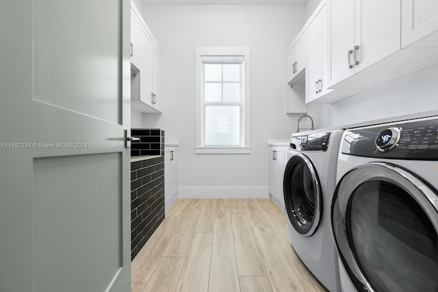 clothes washing area featuring cabinets, separate washer and dryer, and light hardwood / wood-style flooring