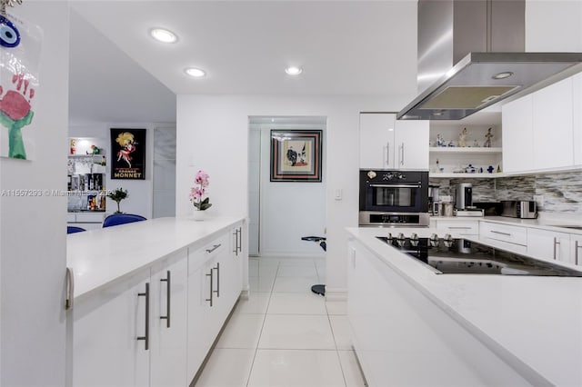 kitchen with white cabinets, black electric cooktop, light tile flooring, wall chimney exhaust hood, and stainless steel oven