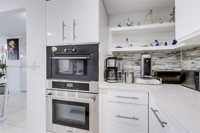 kitchen featuring white cabinets, backsplash, double oven, and light tile flooring