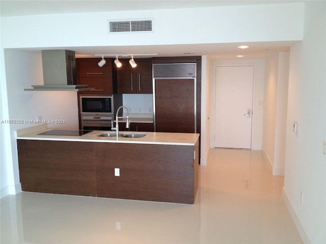 kitchen featuring rail lighting, black appliances, dark brown cabinetry, range hood, and sink