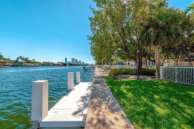 view of dock with a water view and a lawn