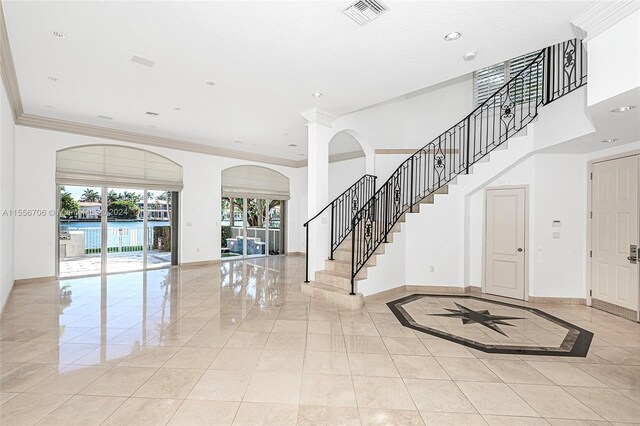 foyer with ornamental molding and light tile patterned floors