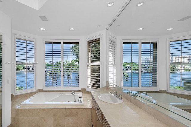 bathroom featuring a whirlpool tub, a water view, recessed lighting, and vanity