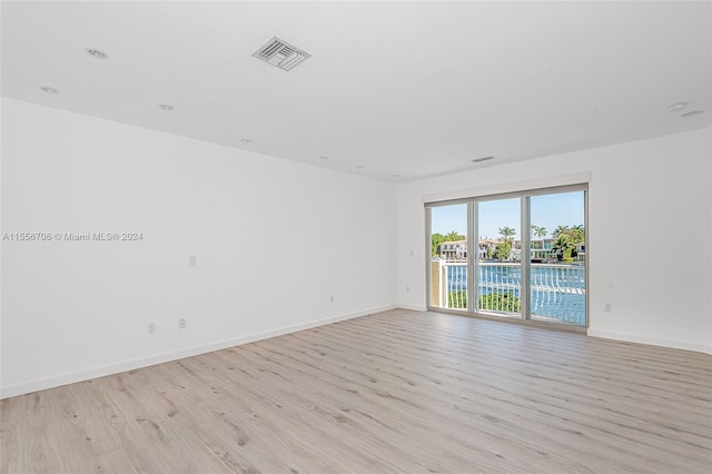 unfurnished room featuring light wood-type flooring, visible vents, and baseboards